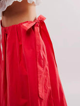 Load image into Gallery viewer, Woman wearing Boho maxi skirt with side bow tie and pockets in red. Side closeup view of bow tie- Gypsy Collection women&#39;s skirt
